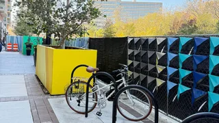 Bike in bike rack and yellow painted box around tree on sidewalk.