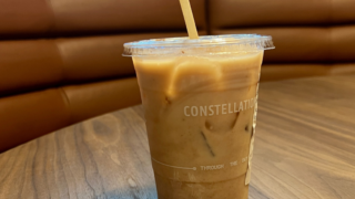 Iced coffee in plastic cup that says Constellation, two star stickers on table.