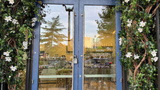 Front door of Maman café with flowers and shrubbery around the frame.