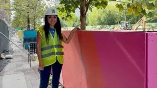 Woman in construction vest and hardhat standing next to pink tree box.
