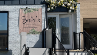 White brick building with pink sign for Zola's Nail Boutique